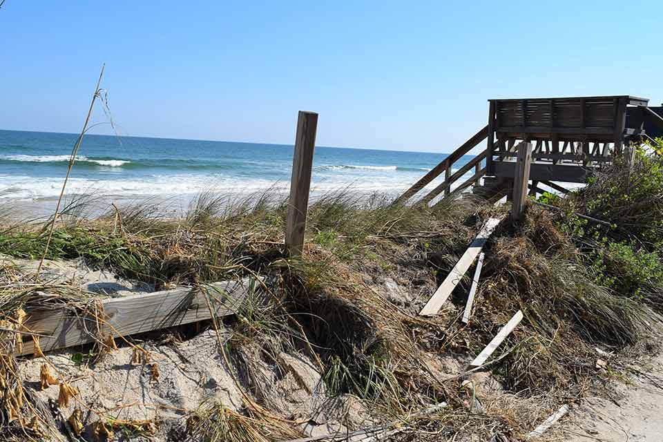 Damaged sand dune and fence.